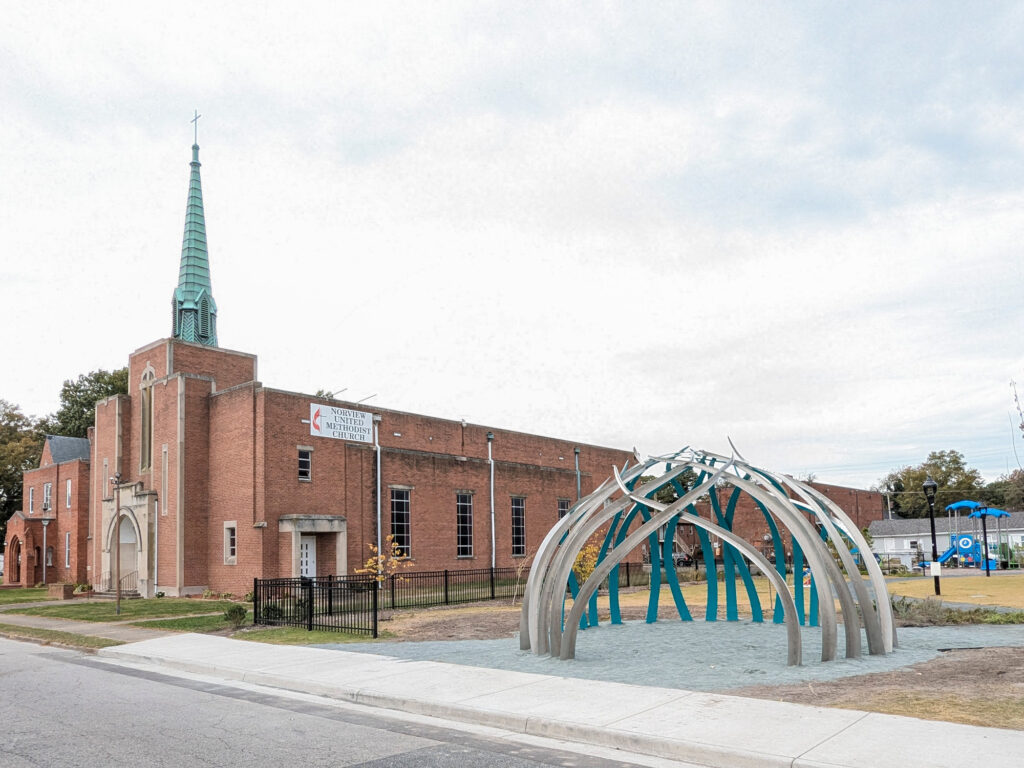 Resilience large-scale public art sculpture in Norfolk Virginia featuring curved steel blades of grass forming a circular dome gathering space